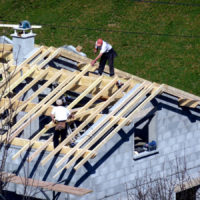 construction workers building a roof of a house