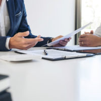 business man looking at contracts and explaining to client business man looking at contracts and explaining to client