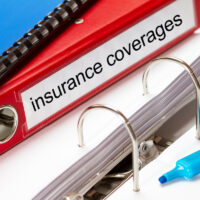 large red folder for insurance coverages including blue ring binder and blue marker