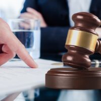 Male hand pointing a place to sign a paper and wooden gavel