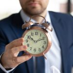 Close up of businessman hold clock showing time limit