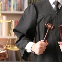 Male judge with gavel and scales of justice in library