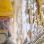 A close up of a professional using a respirator and safety glasses while carefully removing lead paint from damaged drywall, A close up of a professional using a respirator and safety glasses while carefully removing lead paint from damaged drywall,