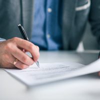 Businessman hand signing contract, close-up.